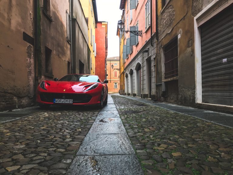 A Ferrari 812 Superfast parked in an alley in the historic center of Modena